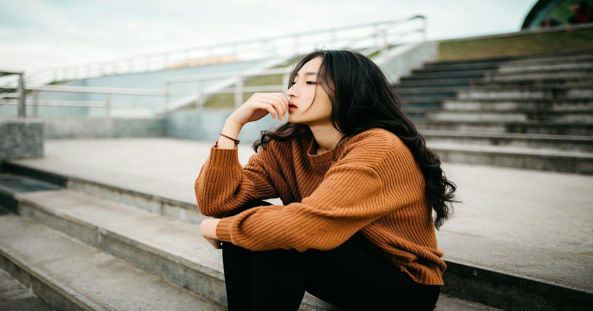 Young woman sitting looking thoughtful