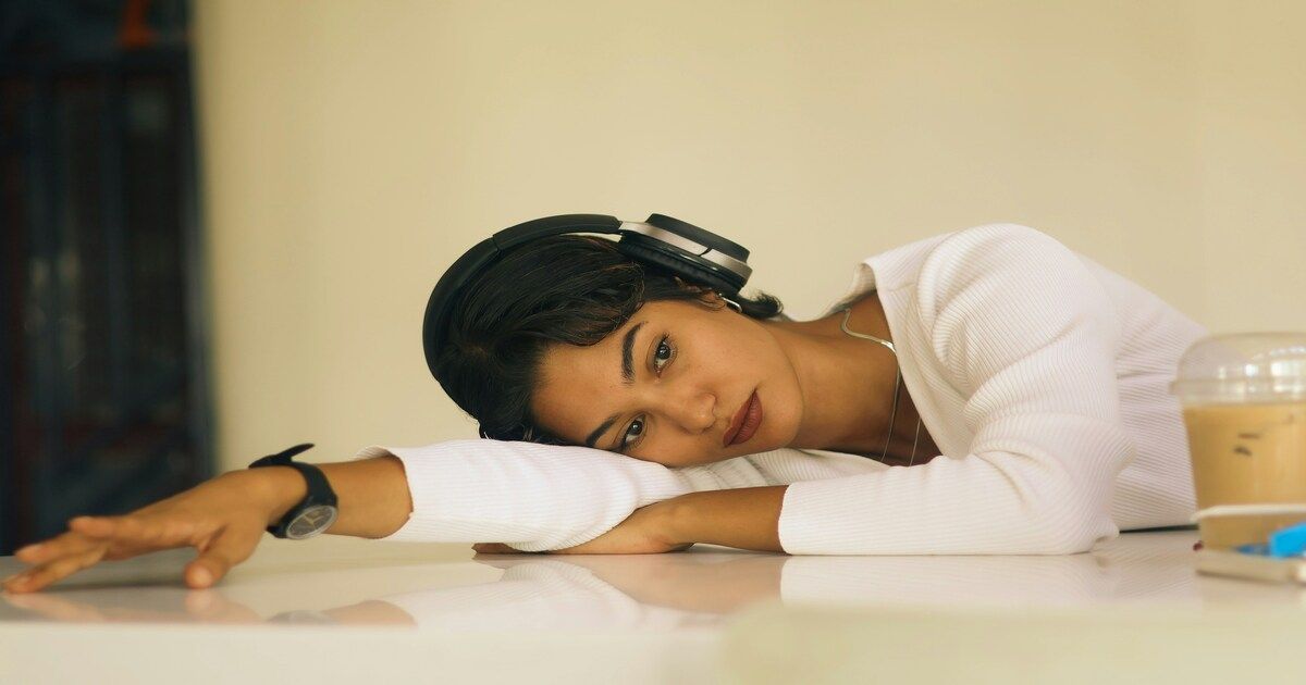 A young Nigerian woman resting her head on a table, looking emotionally drained and exhausted