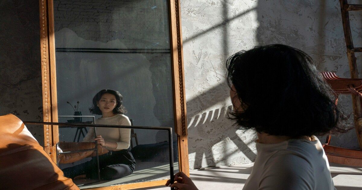 A person looking at their reflection in a window