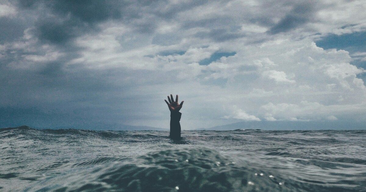 Hand reaching out from the ocean, symbolizing struggle, seeking help, and the journey toward emotional resilience.