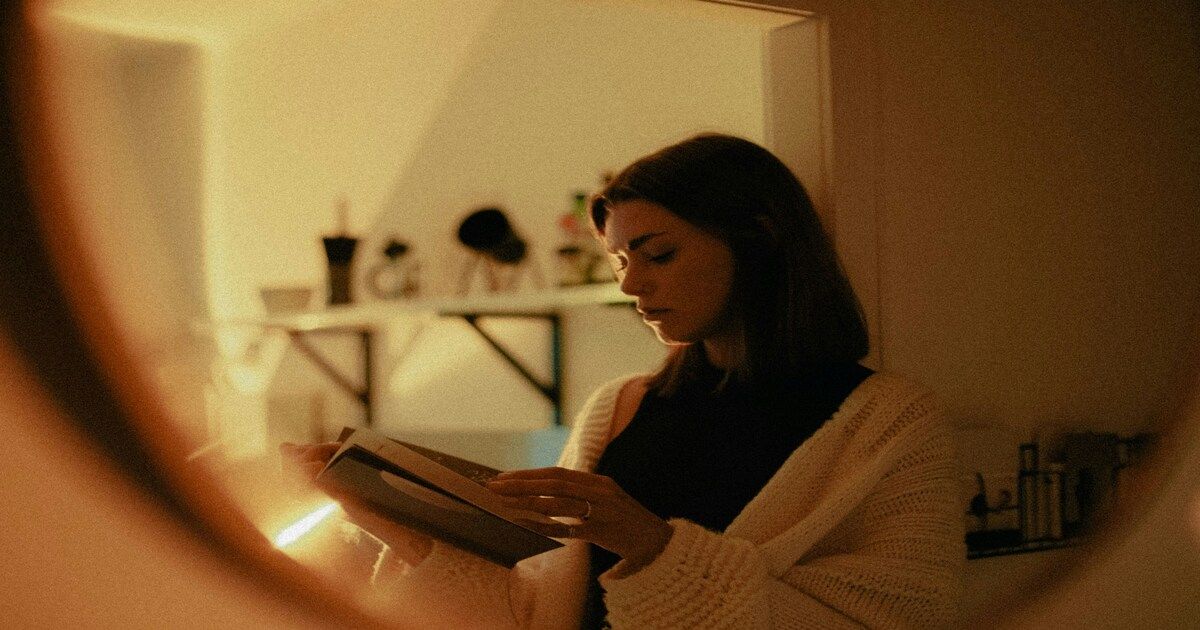 A woman flipping through the pages of a book in a softly lit room.