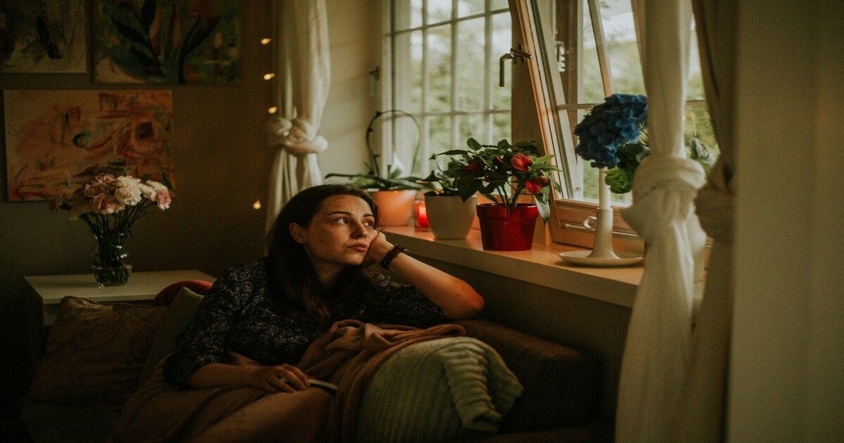 Person sitting by a window looking tired and reflecting