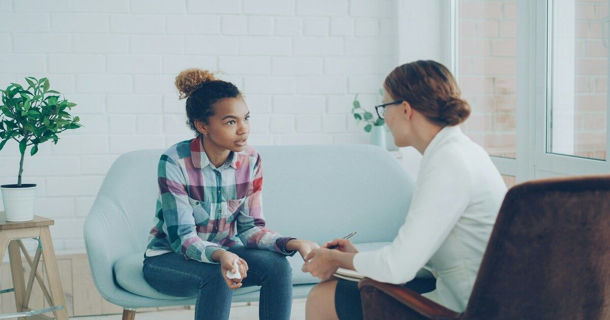 A therapist and client sitting across from each other during a counseling session, engaged in open conversation